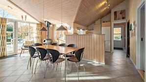A modern kitchen with wooden cabinets, a central island, and a dining area with a wooden table and chairs.