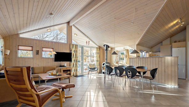 A spacious living area with a wooden interior, a fireplace, and a kitchen area with a refrigerator.