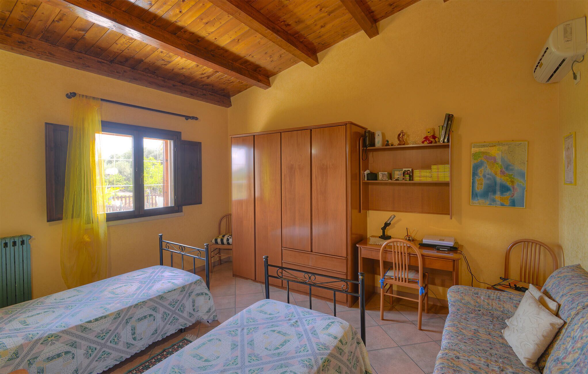 A room with two beds, a desk, a chair, a wardrobe, and a radiator.