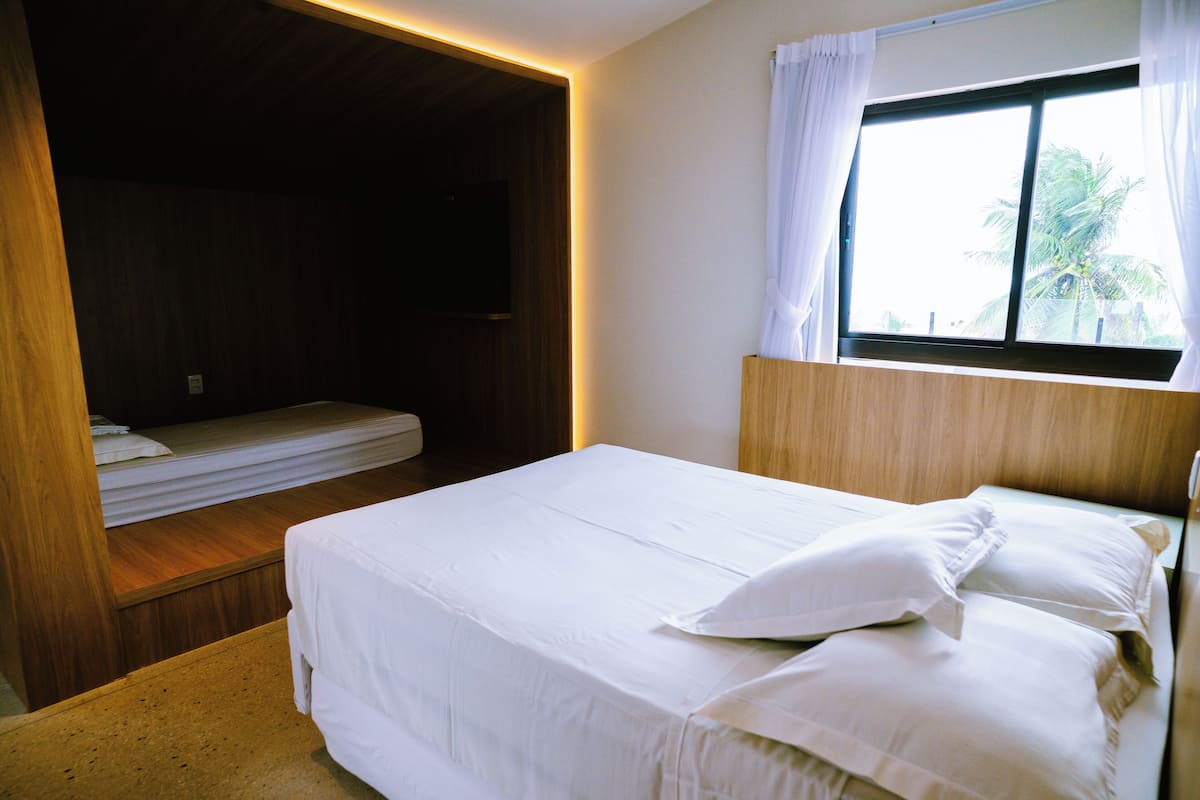 Un dormitorio con cama, ventana con cortinas y cabecero de madera.