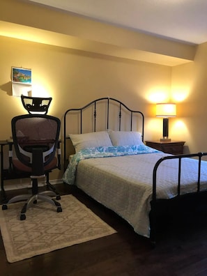 A neatly arranged bedroom with a bed, a chair, a nightstand, and a lamp.