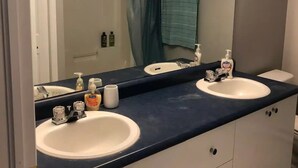 A bathroom with two sinks, a large mirror, and a shower curtain.