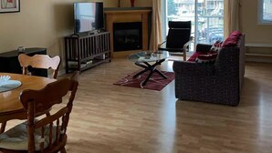 A living room with a fireplace, a television, a sofa, and a dining table with chairs.