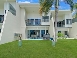 Ein modernes, zweistöckiges Gebäude mit überdachter Terrasse, Außenbereich mit Sitzgelegenheiten und einem Schwimmbecken.