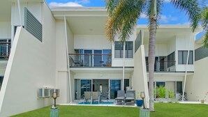 A modern two-story building with a covered patio, outdoor seating, and a swimming pool. - Magnetic Docks Townhouse 8 (Nelly Bay)