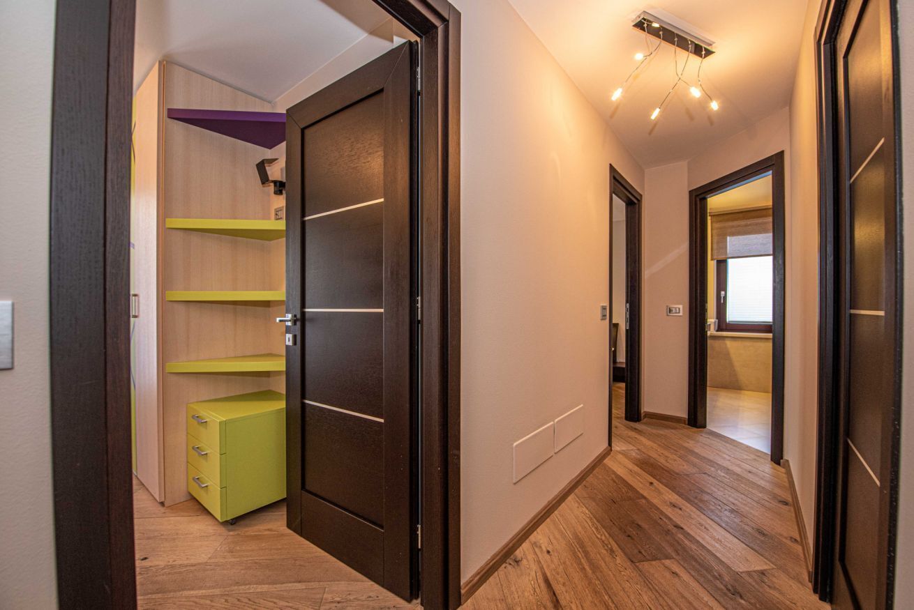Ein Flur mit Holzdielen, einer Glastür und einem grünen Schrank.