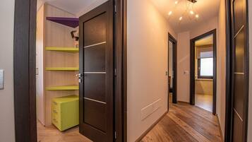 Ein Flur mit Holzdielen, einer Glastür und einem grünen Schrank.