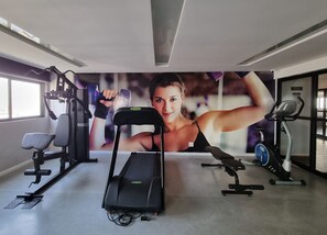 A gym with exercise equipment, a treadmill, and a large motivational poster on the wall. - Apê c/ Ar, Wi-Fi, Piscina, Vista Mar e Garagem (Maceió)