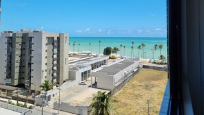 Uitzicht op een kustgebied met een complex van gebouwen, een parkeerplaats en een strand met palmbomen.
