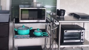 Eine Küchenzeile mit Mikrowelle, Toasterofen und einem Wagen mit Töpfen und Pfannen.