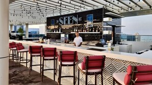 A modern bar with a black and white color scheme, bar stools, and a city view. - 532 SEVEN PALM by Design Studio (Dubai)