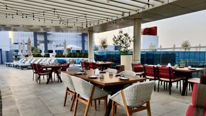An outdoor dining area with multiple tables and chairs, some with umbrellas. - 532 SEVEN PALM by Design Studio (Dubai)