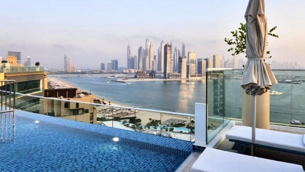 A rooftop pool with a city skyline view, including tall buildings and a body of water. - 532 SEVEN PALM by Design Studio (Dubai)