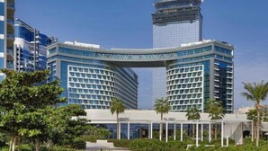 A modern hotel with a distinctive curved entrance, surrounded by lush greenery and palm trees. - 532 SEVEN PALM by Design Studio (Dubai)