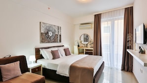 A hotel room with a bed, a sofa, a desk with a lamp, a mirror, and a television. - Hotel La Mer  (Becici)