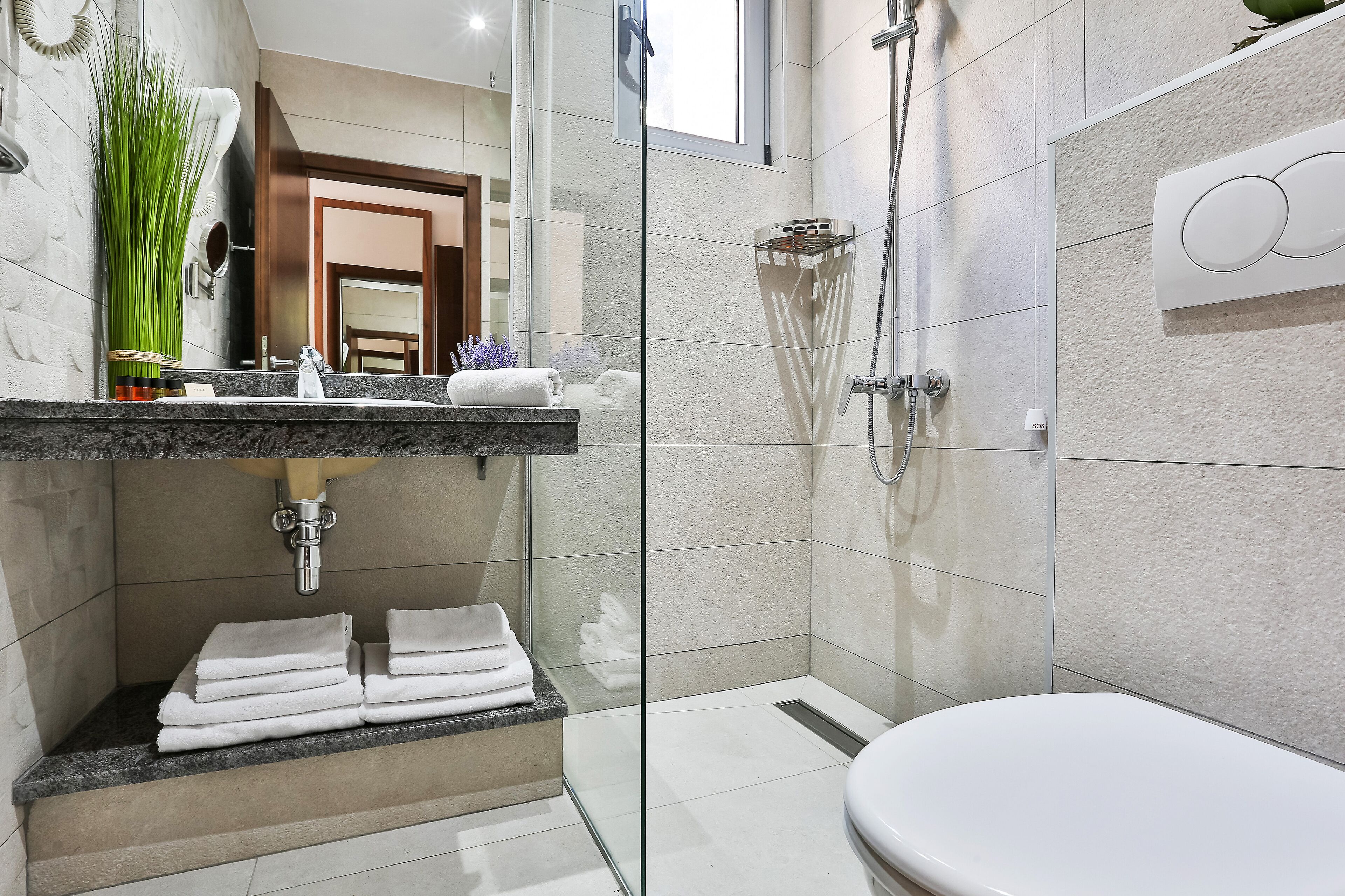 A modern bathroom with a glass-enclosed shower, a marble countertop, and a white toilet.