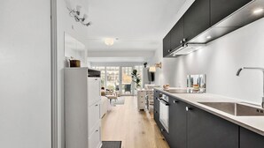 Eine moderne Küche mit einer zentralen Kochinsel, einem eingebauten Ofen und einem großen Fenster mit Blick auf einen Garten.
