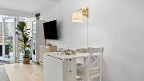 Ein modernes, minimalistisches Zimmer mit weißem Schreibtisch, Flachbildfernseher an der Wand und einer außergewöhnlichen Wandleuchte.
