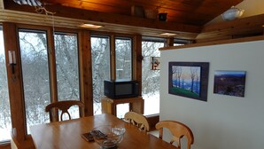 Una mesa de madera con sillas, un bol de vidrio y un televisor sobre un mueble.
