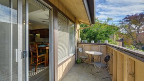 Een balkon met een schuifdeur naar een eethoek, een klein rond tafeltje en twee stoelen.