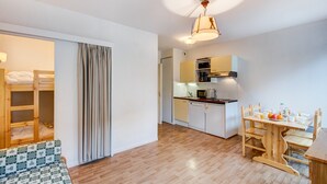Un espacio habitable compacto con kitchenette, comedor y zona de descanso con literas.