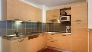 Eine moderne Küche mit Holzausbau, einer Edelstahlspüle und einer Mikrowelle.