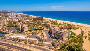A resort with multiple buildings, a beach, and a clear blue sky.