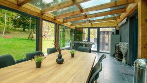A modern dining area with a wooden table, chairs, and potted plants.