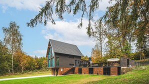 A modern house with a sloped roof, large windows, and a visible staircase leading to the entrance.