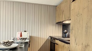 Une cuisine moderne avec des meubles en bois, un plan de travail noir et une cuisinière intégrée.