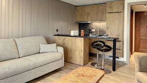 Une cuisine moderne avec des meubles en bois, un plan de travail noir et un tabouret de bar.