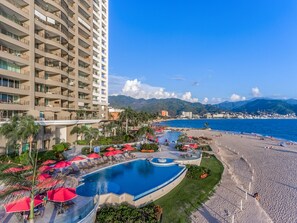 Ein Hotel mit Pool, Strand und Bergblick.