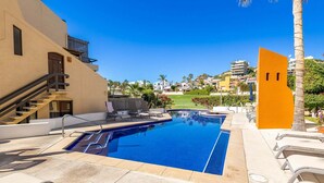 A swimming pool with a clear blue water, surrounded by lounge chairs and a staircase leading to an upper level. - Charming Retreat: 1-Bedroom Condo in Historic SJD (San José del Cabo)
