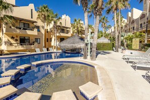 Un espace piscine d’hôtel avec des chaises longues et des palmiers.