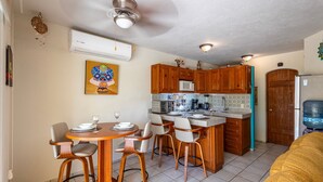 A compact kitchen with wooden cabinets, a microwave, and a water dispenser. - Charming Retreat: 1-Bedroom Condo in Historic SJD (San José del Cabo)