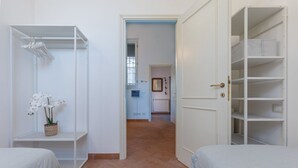 A bedroom with a bed, a wardrobe, and a small shelf with a plant. - GuestHost - Manfredini Historical House in the heart of Ferrara (Ferrara)