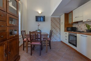 Une cuisine équipée d’une table à manger, de chaises, de placards, d’un téléviseur et d’un four à micro-ondes.