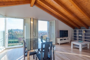 A spacious room with a dining area, a TV, and a bookshelf.