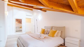 Een slaapkamer met een bed, nachtkastjes en houten balken aan het plafond.
