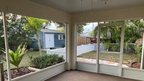 A covered patio area with a view of a backyard, including a small shed and a fenced play area. - Charming 3-bedroom house in Englewood within minutes of beaches and golf. (Englewood)