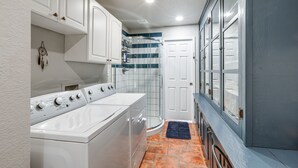 Un área de lavandería con lavadora y secadora, una ducha con puerta de vidrio y una puerta que da a un garaje.