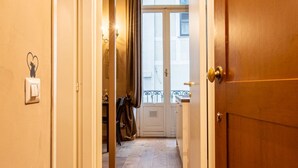 A hallway with a door leading to a balcony, a light switch, and a coat hanging on the wall. - Atriums Apartment Quovis Domus, an enchanting nest in the heart of city centre (Torino)