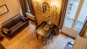 A dining area with a table, chairs, a sofa, and a window with curtains. - Atriums Apartment Quovis Domus, an enchanting nest in the heart of city centre (Torino)