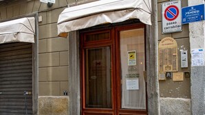 A building with a closed shutter, a wooden door, and a sign indicating a no parking zone. - Atriums Apartment Quovis Domus, an enchanting nest in the heart of city centre (Torino)
