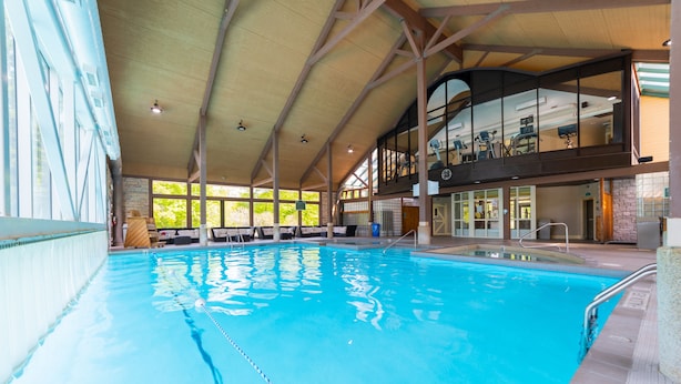 An indoor swimming pool with clear lanes, a high ceiling, and a view of the upper level with exercise equipment. - Horseshoe Valley Suites - The Azure (Oro-Medonte)
