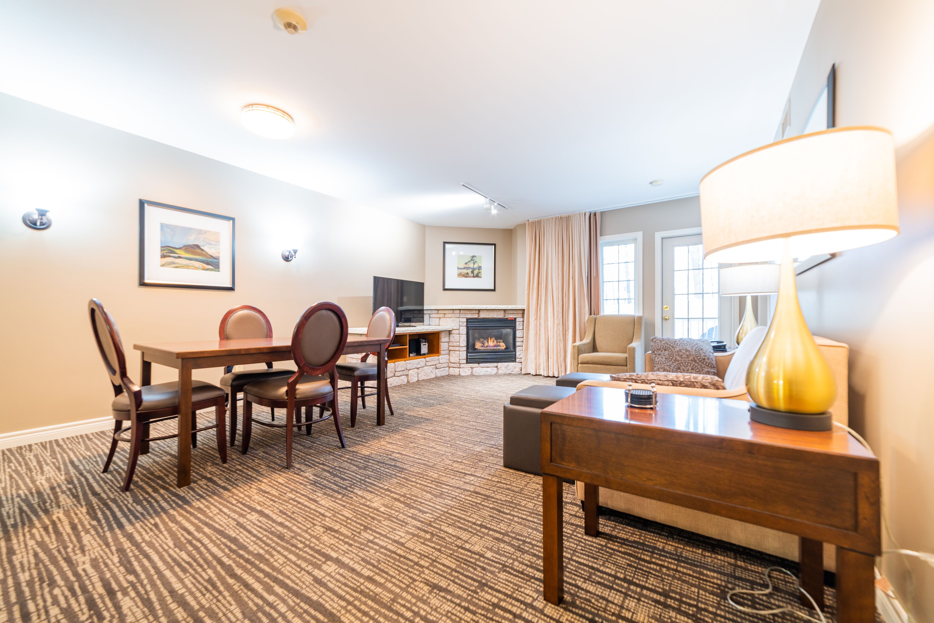 A hotel room with a dining area, a sofa, a lamp, and a fireplace.