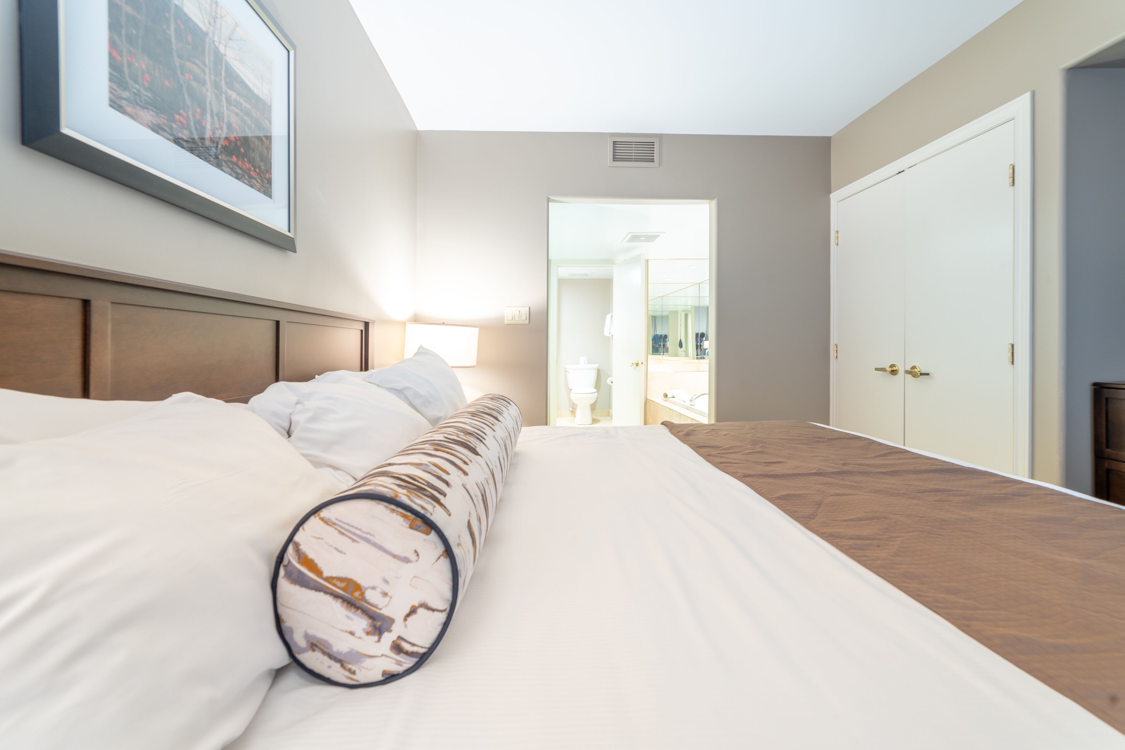 A hotel room with a large bed, a headboard, a bedside table, and a framed picture on the wall.