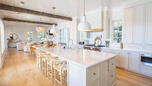 A spacious kitchen with a large island, white cabinetry, and wooden flooring. - Gulf Bridge by Stay on 30a (Inlet Beach)