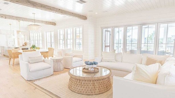 A spacious living room with a large white sofa, a round coffee table, and a dining area with a chandelier. - Gulf Bridge by Stay on 30a (Inlet Beach)