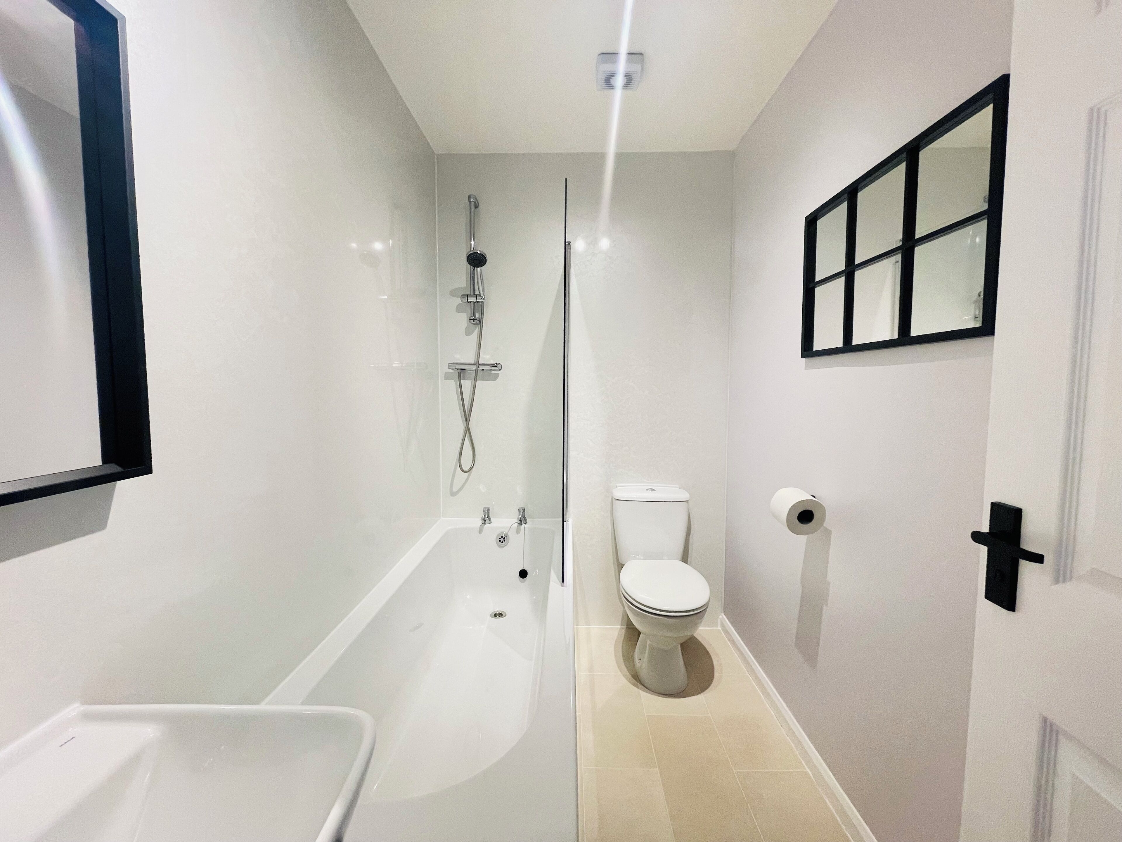 A modern bathroom with a bathtub, toilet, and shower.